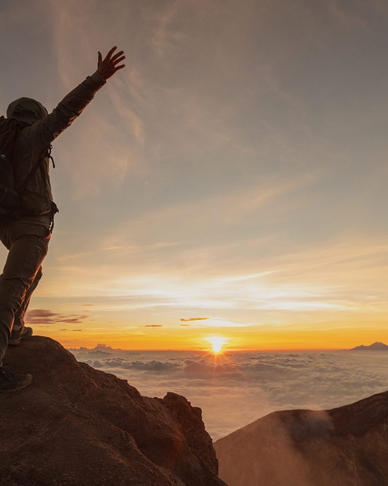 Trekker silhouette standing on the summit of Mount Rinjani at 3,726 metres at sunrise